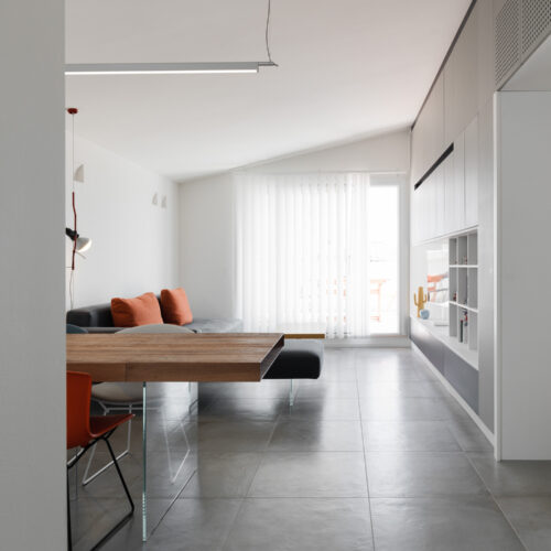 1 B0037045 soggiorno con gres arredo contenitore su misura tavolo lago sospeso air e illuminazione a sospensione flos parentesi luceplan compendium